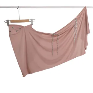 Detail view of solid color pink wrap scarf featuring metallic tassel chains and chic camellia decor.