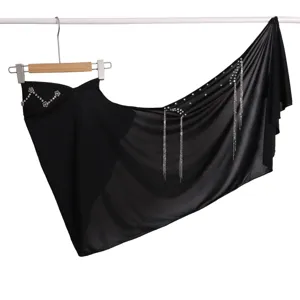 Detailed black asymmetrical wrap skirt featuring sparkling rhinestones and elegant metal tassels.