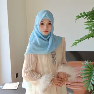 Muslim women solid light blue hijab and beige pleated long dress set with feather cuffs.