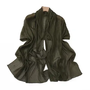 Detail of olive green pleated chiffon scarf with silver threads and pearls, shawl accessory texture.