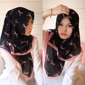 Vue rapprochée du foulard en mousseline noire avec de jolis motifs de nœuds roses.