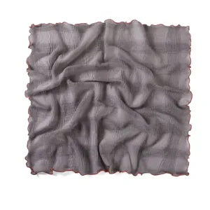 Close-up detail of gray crinkled square scarf with vibrant orange lettuce edge texture.
