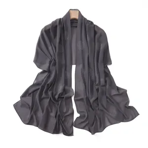 Detail view of dark gray chiffon scarf featuring sparkling rhinestone polka dots and elegant drape.