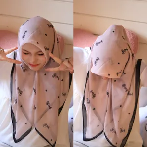 Vue détaillée du foulard rose en mousseline avec imprimé de roses et cœurs porté naturellement.