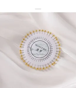 Vue détaillée d'épingles à tête de perle dans un disque de rangement blanc rond.