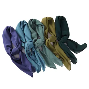 Close-up detail of soft chiffon square headscarf showing neat knot and smooth fabric texture.