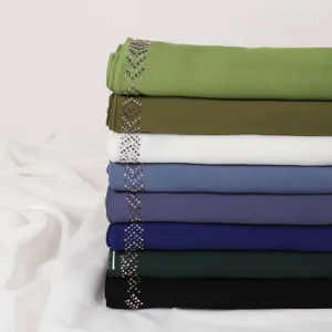 Close-up detail view of stacked colorful chiffon hijabs featuring elegant crystal rhinestone trim.
