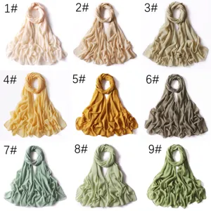 Dettaglio di sciarpa in chiffon tinta unita con dettagli dorati e diverse opzioni di colore.