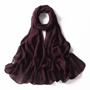 Primo piano di una sciarpa hijab in chiffon viola scuro con brillantini dorati leggeri.
