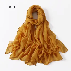 Detail view of the lightweight solid color polyester long scarf in mustard yellow, soft texture.