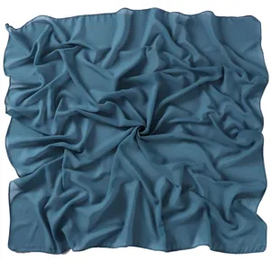 Detail view of the solid blue chiffon square scarf texture, elegant draping and lightweight fabric.