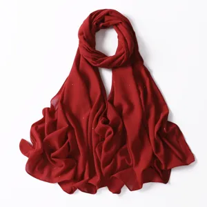 Dettaglio sciarpa lunga in chiffon rosso, macchioline dorate, texture tessuto drappeggiato.