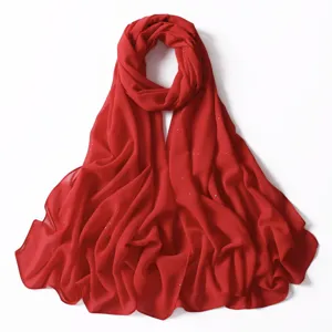 Sciarpa in chiffon rosso scintillante in primo piano, dettagli di tessuto leggero e oro.