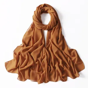 Vista dettagliata del foulard in chiffon dorato, tessuto leggero con scintillanti dettagli.
