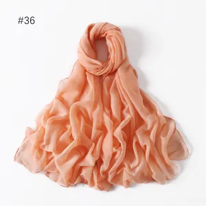 Detailed view of the lightweight solid color peach pink polyester voile long scarf closeup.