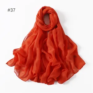 Lightweight solid color polyester voile scarf detail view, soft draped fabric, orange.