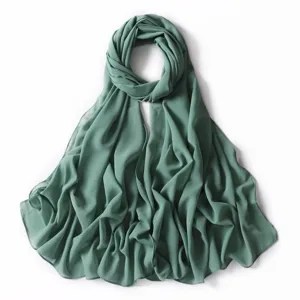 Vista dettagliata della sciarpa in chiffon tinta unita con pois dorati, elegante hijab da donna.