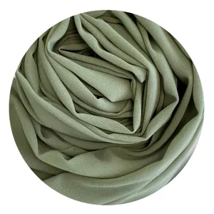 Close-up detail of soft green chiffon hijab fabric, showing elegant pleats and smooth texture.