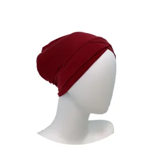 Close-up detail of the deep red modal cross turban inner cap, smooth texture, hijab under-cap.
