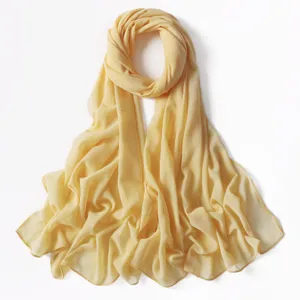Vista dettagliata della sciarpa lunga in chiffon glitterato giallo chiaro e delicata.