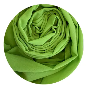 Detail view of the soft green chiffon hijab, showcasing its delicate texture and rolled form.