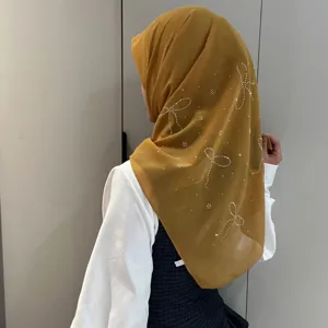 Vue detaillee hijab en mousseline avec noeud strass, accessoire foulard moutarde.