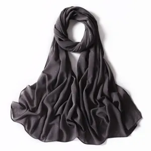 Primo piano della sciarpa in chiffon grigio scuro con pois dorati scintillanti e morbida.
