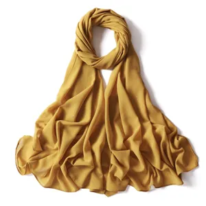 Dettaglio hijab in chiffon scintillante, sciarpa lunga giallo senape, texture morbida.