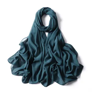 Primo piano dettaglio del foulard hijab scialle in chiffon verde scuro scintillante con pois dorati.