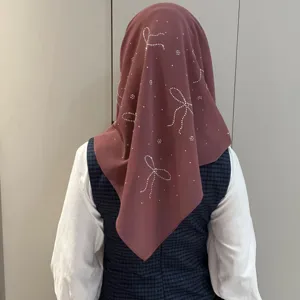 Détail foulard en mousseline avec nœuds en strass au dos, accessoire uni et élégant.