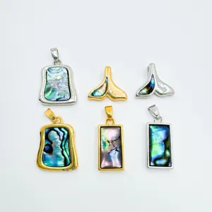 Abalone shell pendant detail shot showing colorful geometric and whale tail designs in gold and silver.