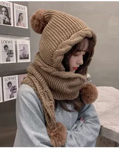 Cozy winter knitted hooded scarf detail showing cute fluffy pom-poms and warm ear protection.