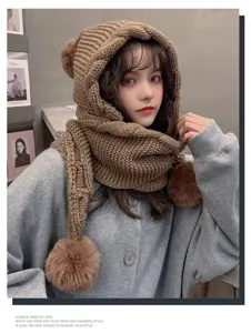 Close-up detail of the cozy knitted hooded scarf with cute pom-poms for winter warmth.