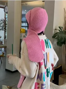 Vue détaillée de la jolie cagoule en tricot rose et de l'écharpe, style d'hiver confortable au café.