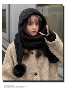 Close-up of stylish black knitted hooded scarf with cute pom-pom, soft winter detail.