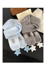 Détail d'écharpe tricotée douillette avec jacquard étoilé et pendentifs en peluche.