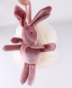 Close-up of cute pink plush rabbit detail with fluffy white mesh bath sponge for body scrub.