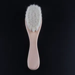 Vue de détail d'une brosse bébé en bois souple avec des poils blancs fins pour le visage.