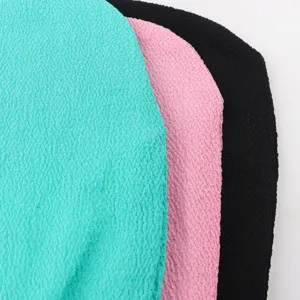 Close-up detail shot of textured exfoliating bath towels in turquoise, pink, and black colors.