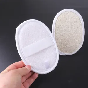 Gros plan d'éponge loofah ovale avec texture naturelle et sangle de main élastique blanche.