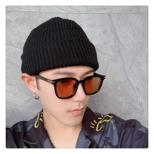Vista detallada del gorro de punto negro y gafas de sol elegantes para hombre, estilo casual.