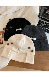 Vue detaillee de bonnets en tricot 100% laine noirs, gris fonce et beiges avec boutons.