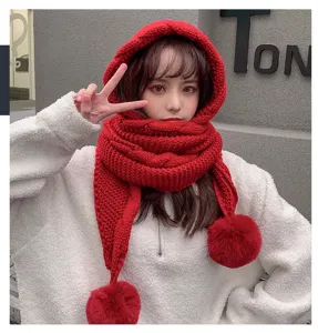 Detailed view of winter red knitted hooded scarf with cute pom-poms and thick plush warmth.