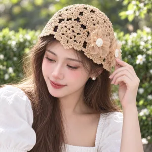 Vue détaillée du bonnet crocheté beige à fleurs ajourées, montrant un tissage fin et des perles.
