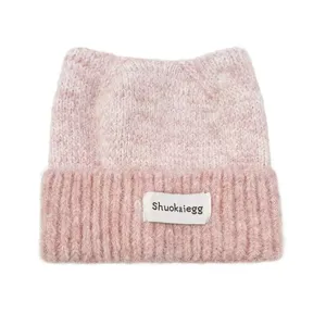 Vue détaillée du bonnet en tricot rose avec oreilles de chat, texture et étiquette.
