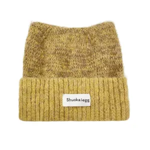 Détail de bonnet en tricot avec oreilles de chat mignonnes, texture duveteuse et vert.