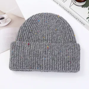 Detailed shot of the thick knitted beanie with colorful speckles, winter warm grey wool hat.