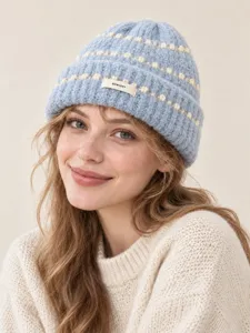 Detail shot of the light blue knit beanie with cozy textured weave and white bobble accents.