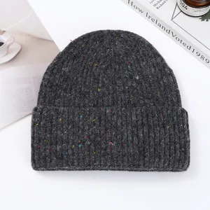 Close-up detail of the dark gray speckled knit beanie, showing soft thick texture and colorful flecks.