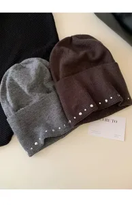 Gros plan détaillé de bonnets en tricot élégants avec strass scintillants et rivets métalliques.